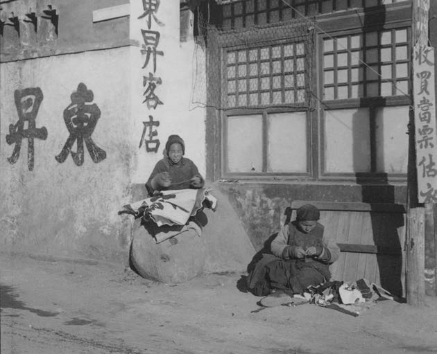 做缝补活儿的妇女在街边的店门口工作（上海教育出版社供图）